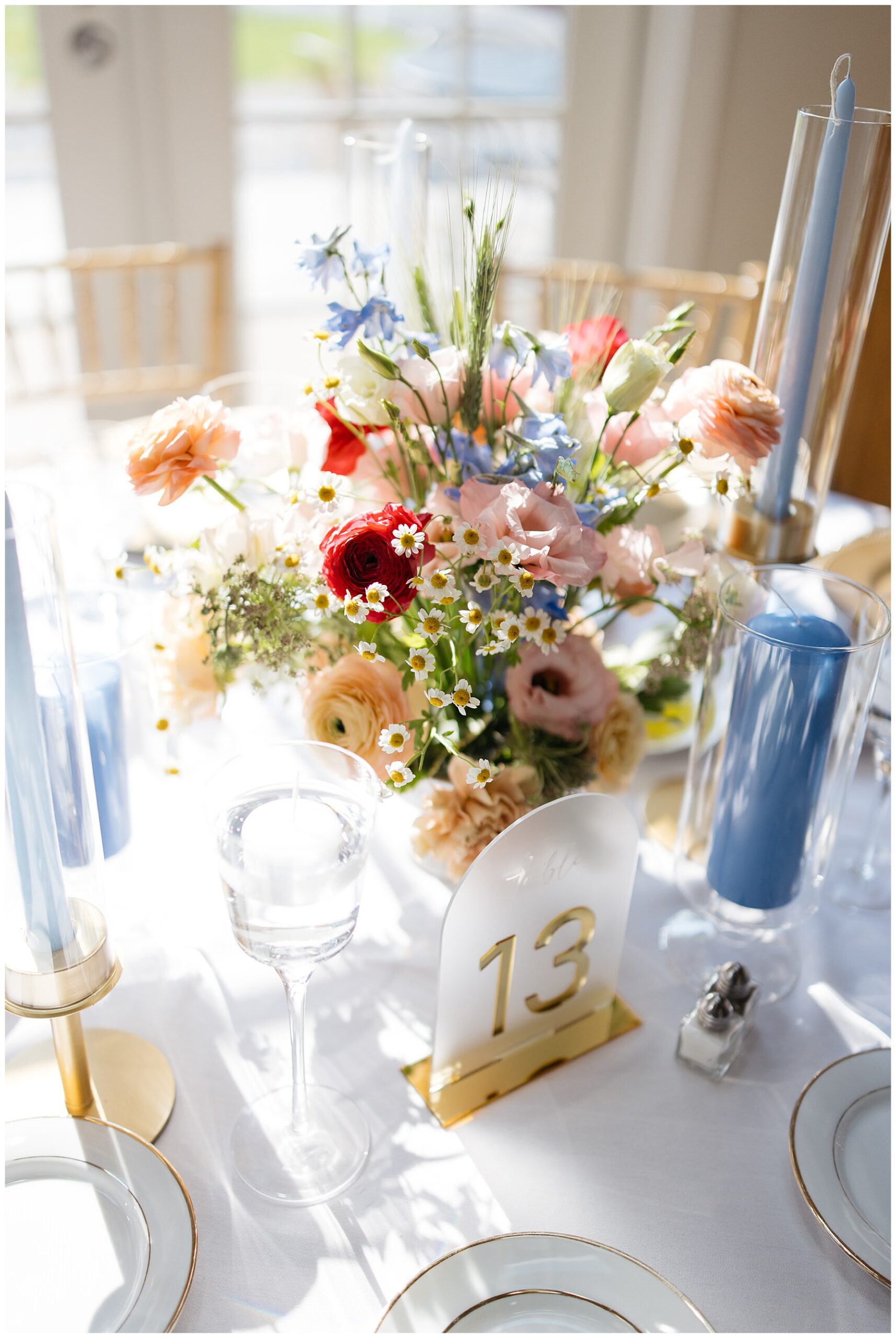 a close up photo of the reception decor with bright wildflowers and light blue candles in the centerpiece 