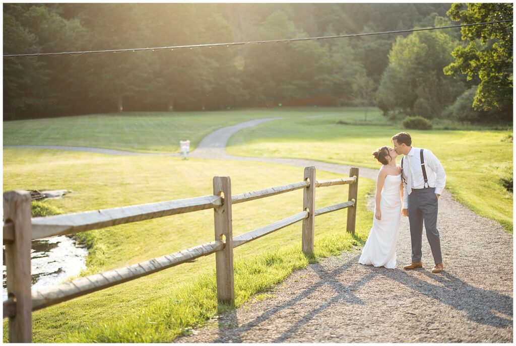 bride and groom walking down a path outside the reception during sunset hour with a beautiful field behind them in the catskills 